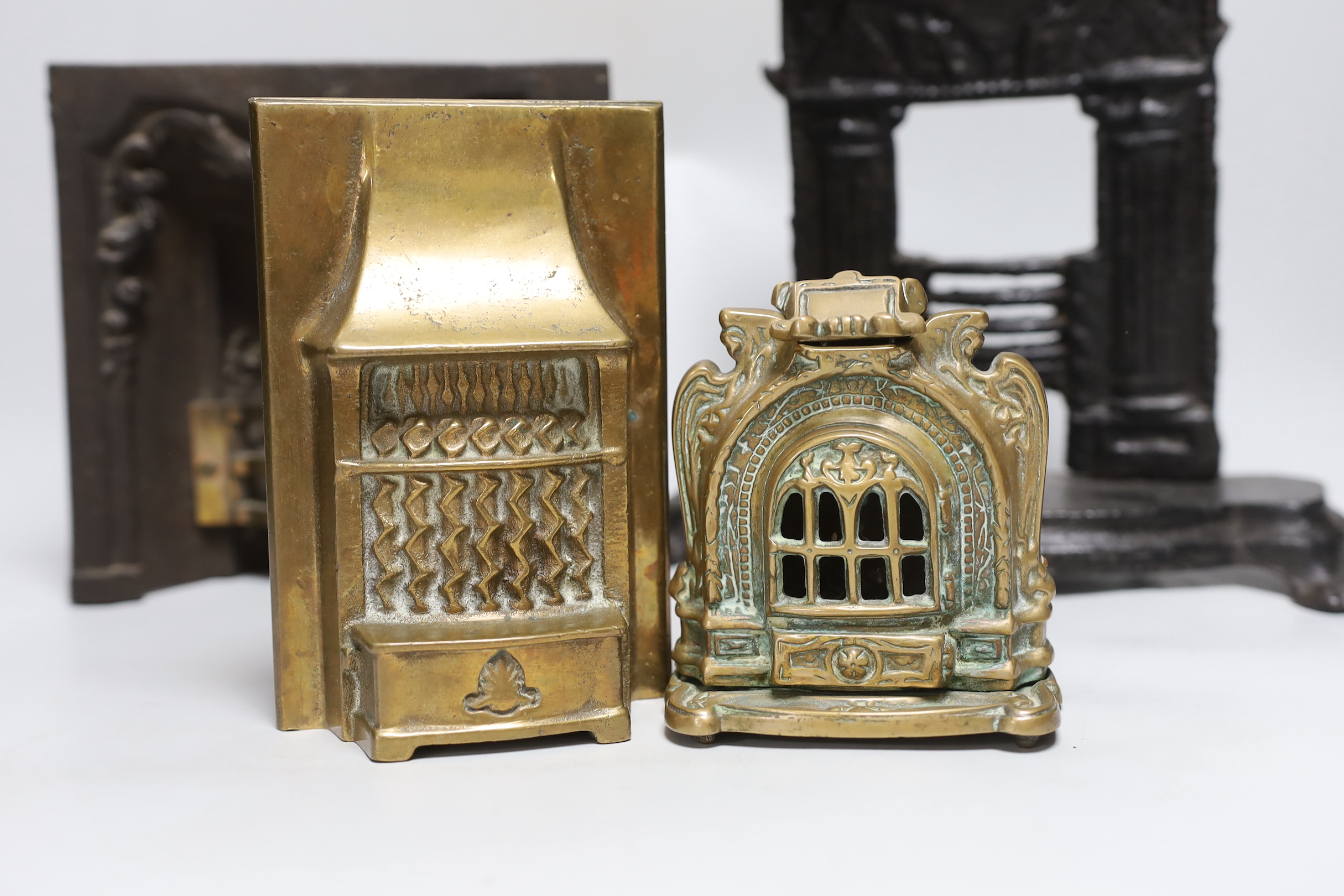 A Victorian cast iron model firegrate, a cast brass model firegrate and a similar stove, tallest 32cm